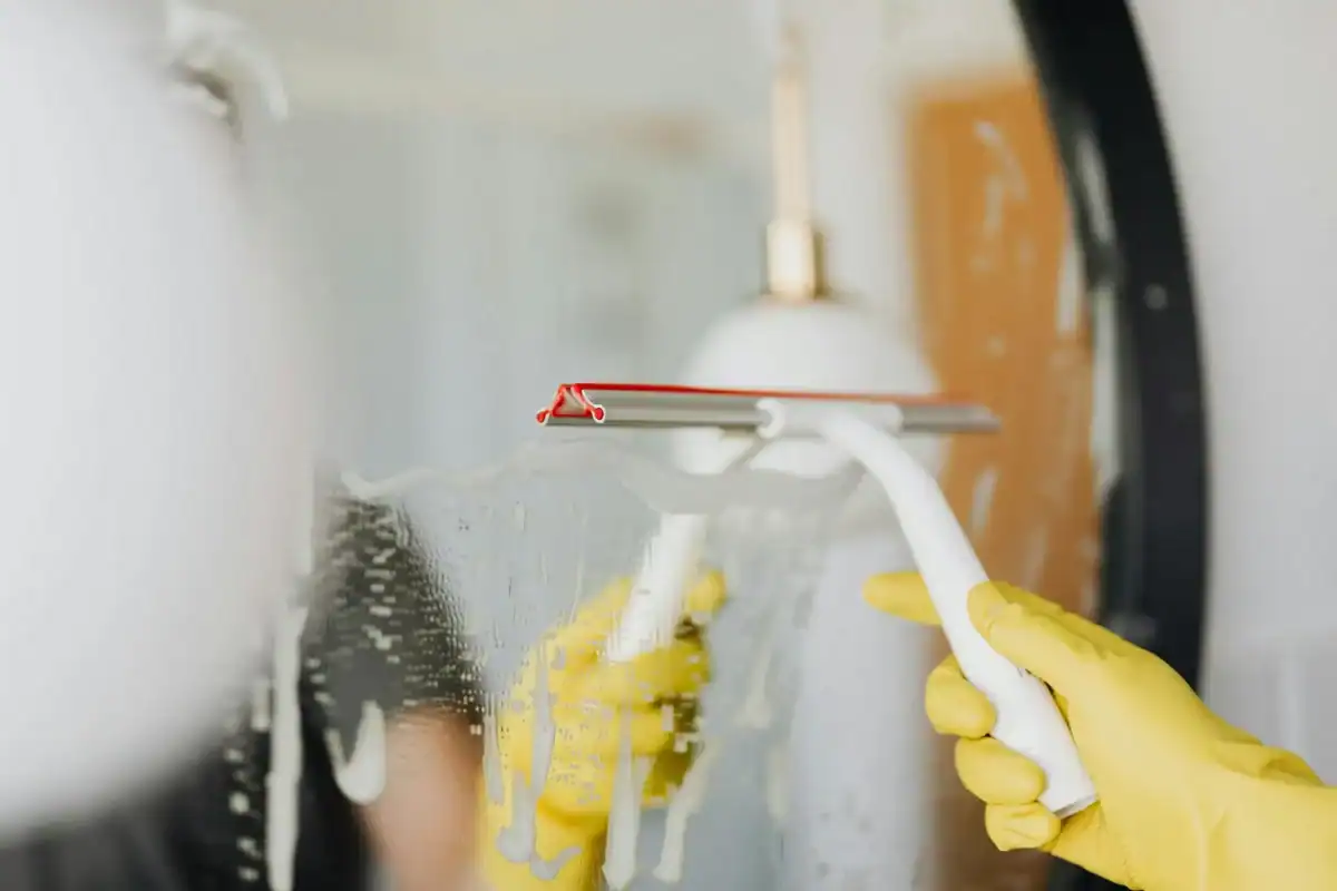 Refrigerator cleaning with squeegee and gloves for spotless, germ-free kitchen surfaces.