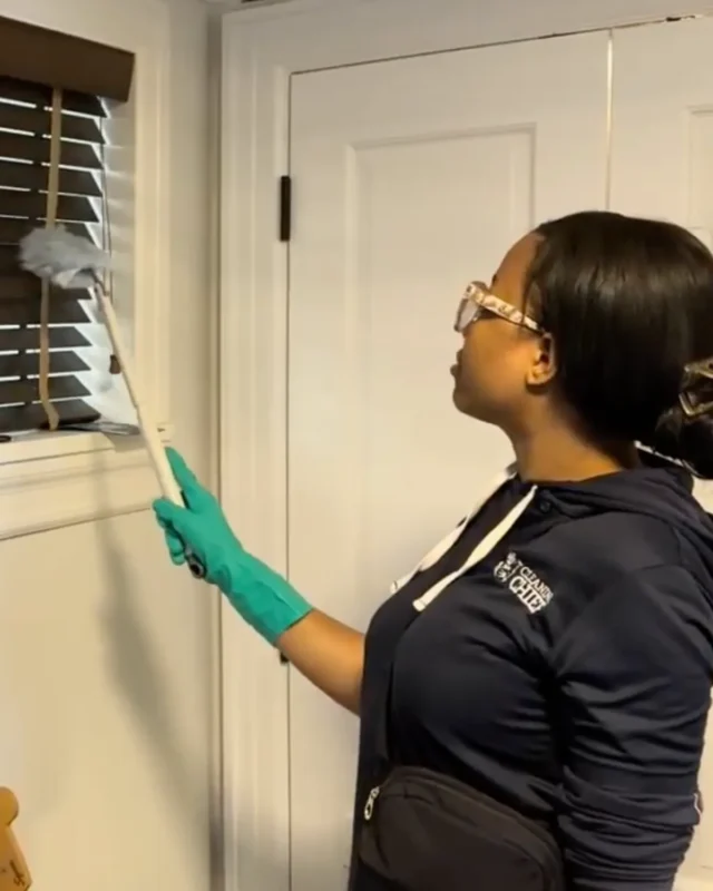 Cleaning Chief cleaner dusting window blinds during Airbnb turnover cleaning in NYC