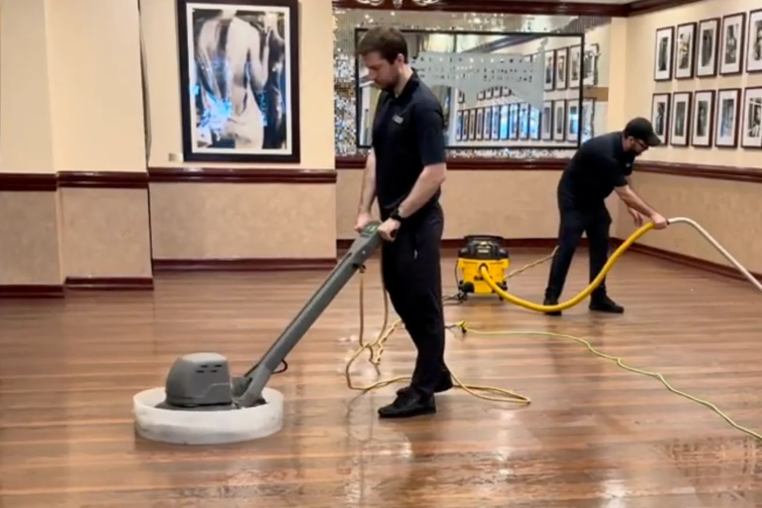 Two Cleaning Chief technicians buffing and polishing hardwood floors with professional rotary machines in a NYC commercial space