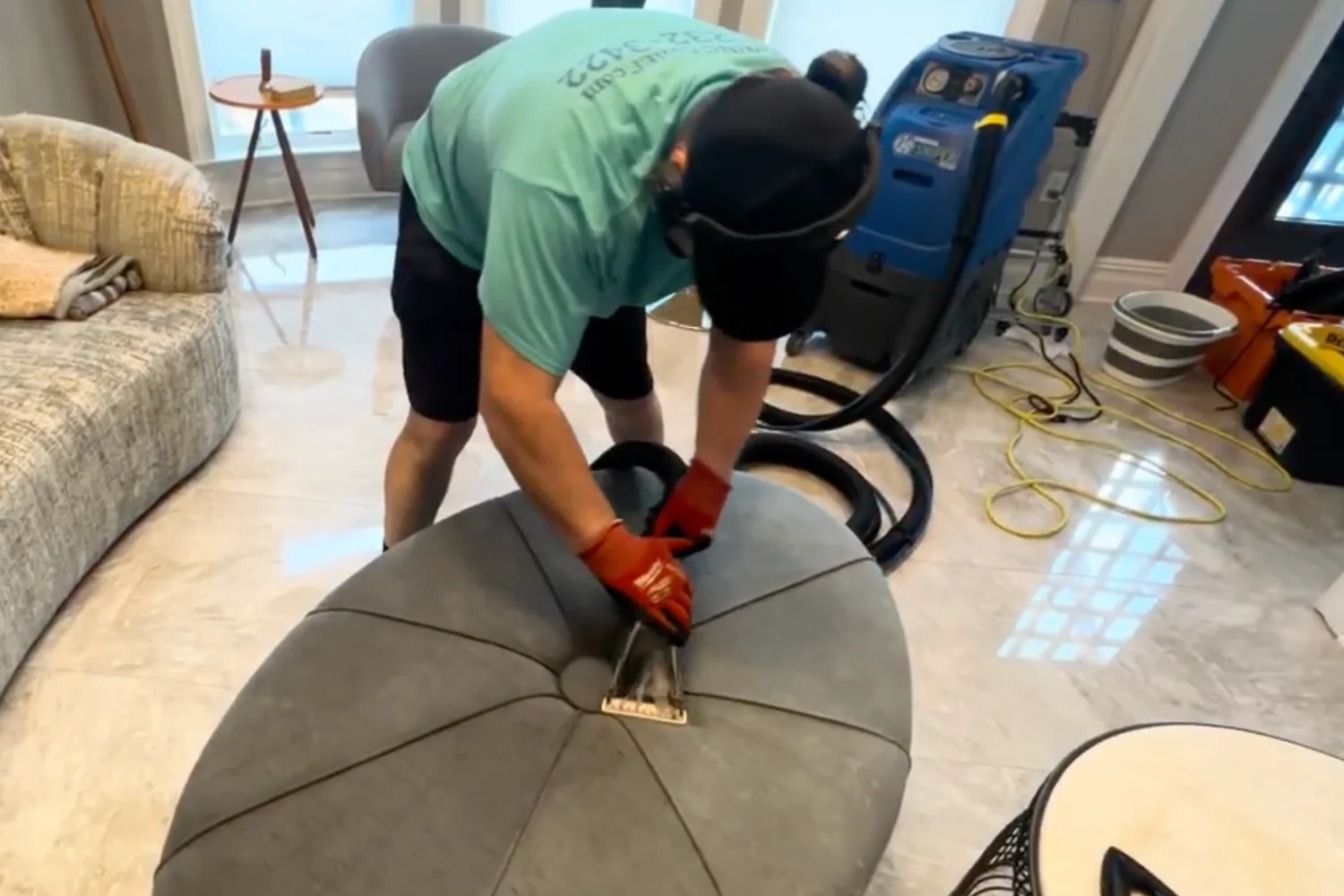 Cleaning Chief technician using a commercial hot-water extraction machine to steam clean an upholstered ottoman in a NYC apartment