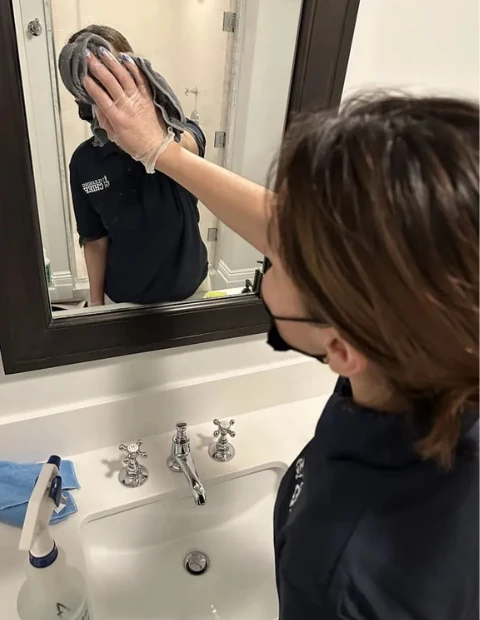 Cleaning Chief NYC VIP cleaner polishing a bathroom mirror in a high-end NYC