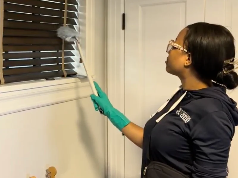 Cleaning Chief NYC VIP cleaner dusting wooden window blinds with a professional duster