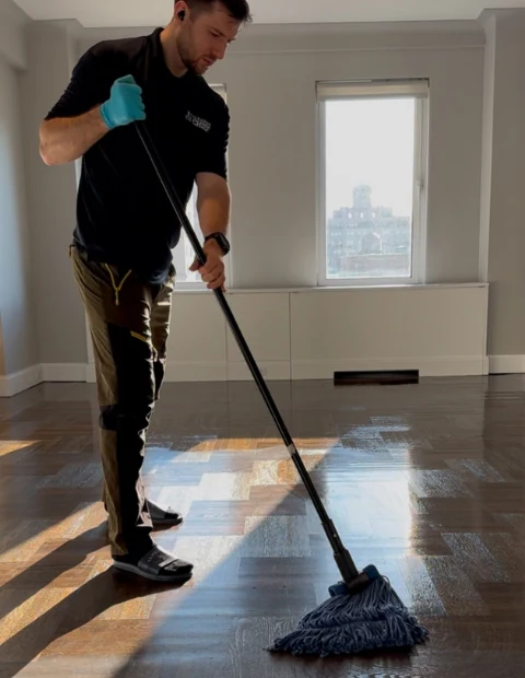 Cleaning Chief NYC VIP cleaner mopping hardwood floors in a luxury Manhattan apartment