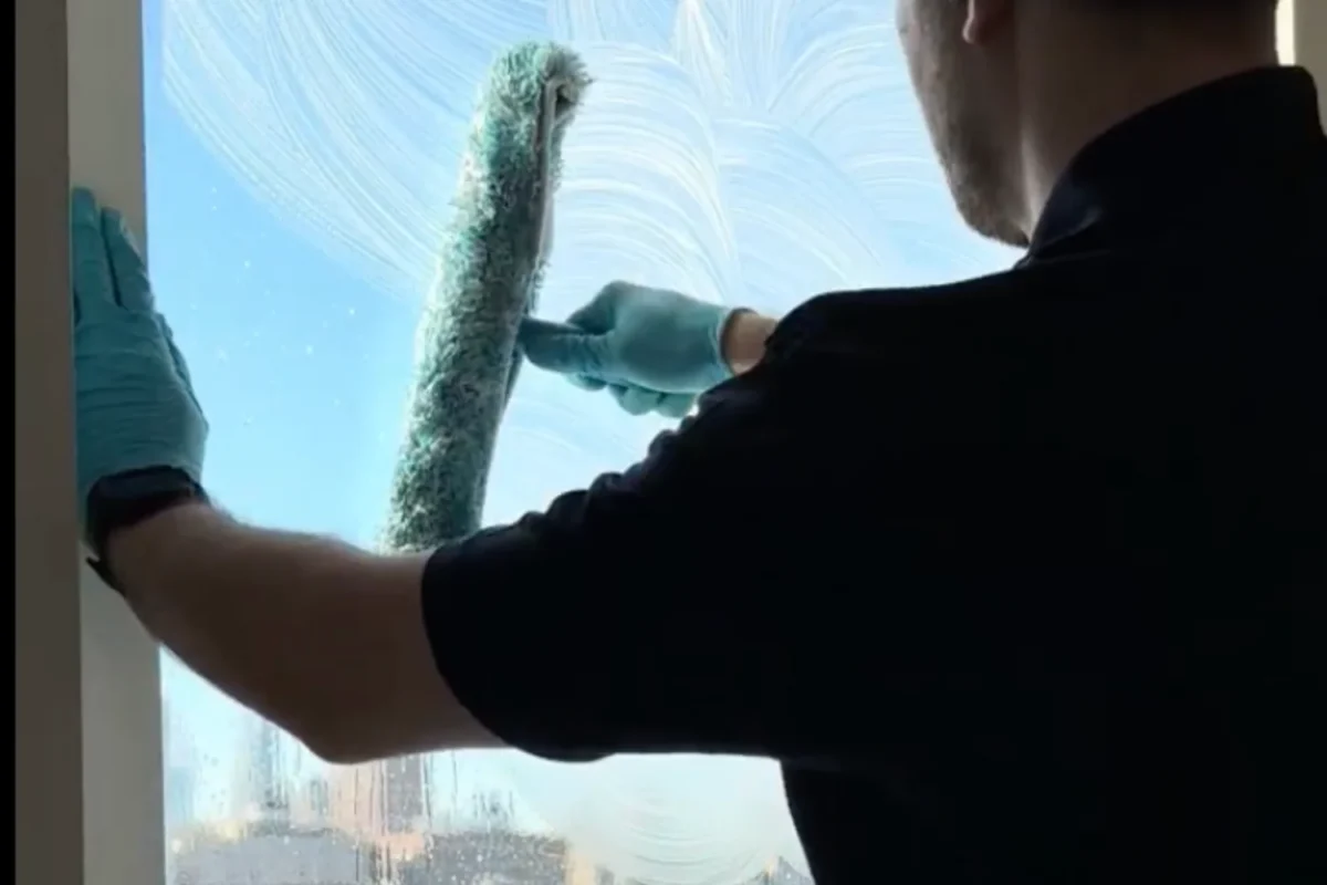 Professional window cleaner squeegeeing glass to a streak-free finish on a New York City building