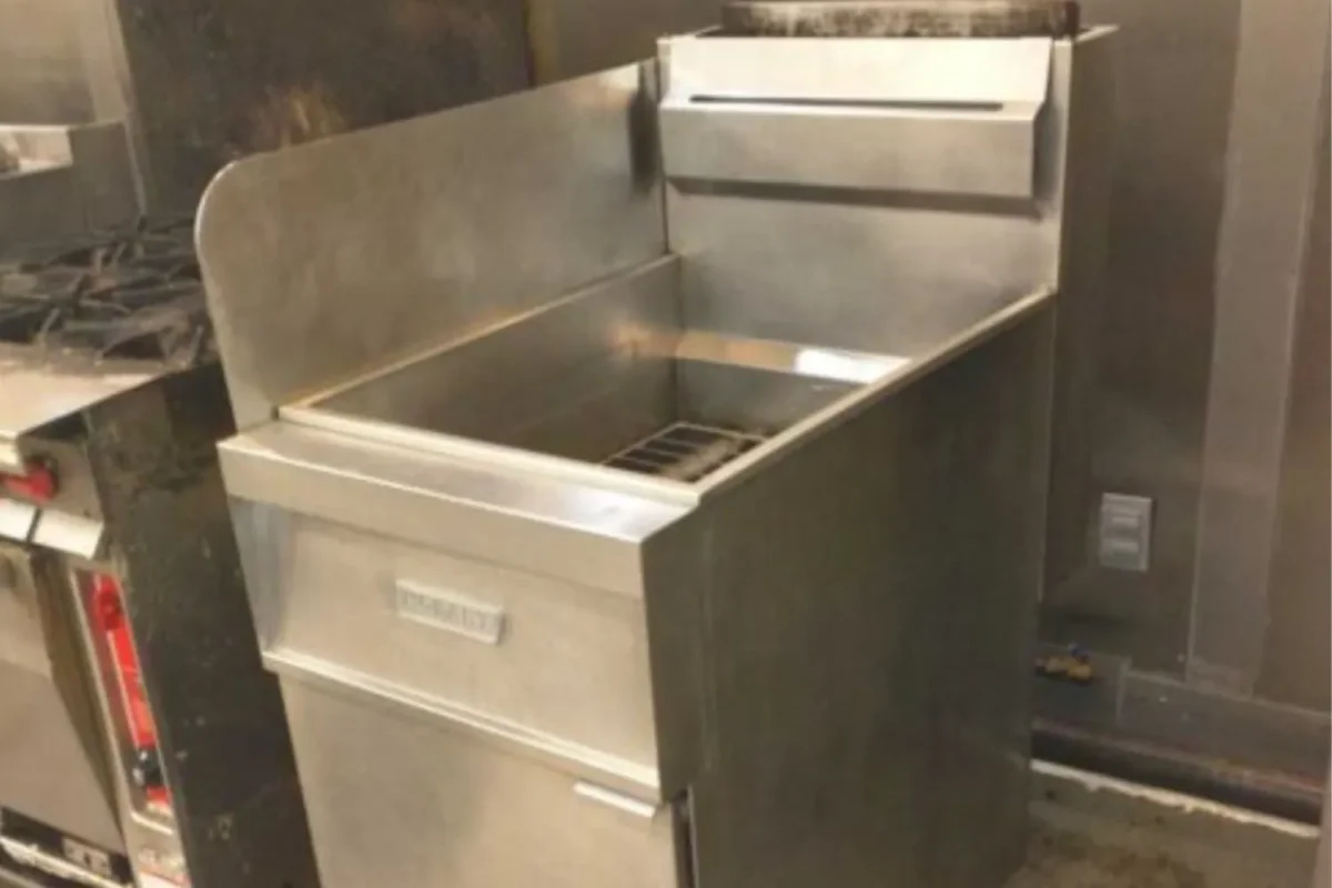 Stainless steel commercial kitchen fryer or sink basin with grease residue and grime before deep cleaning in NYC
