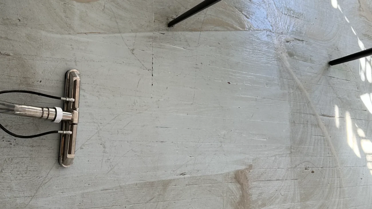 Top-down view of commercial steam cleaning head working on large light stone floor surface during deep cleaning in NYC