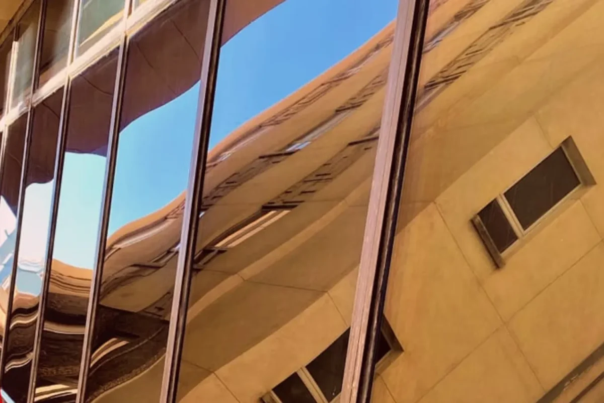 Same commercial glass facade now crystal clear with sharp building and sky reflections after commercial window cleaning