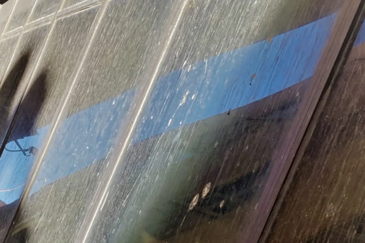 Close-up of commercial glass facade panels heavily streaked with mineral deposits and grime before cleaning in NYC