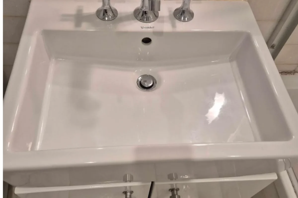 Pristine white bathroom sink with polished chrome faucet after Cleaning Chief deep cleaning in NYC
