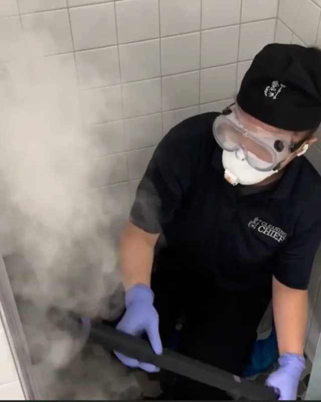 Cleaning Chief cleaner in protective gear using steam cleaner in NYC apartment bathroom