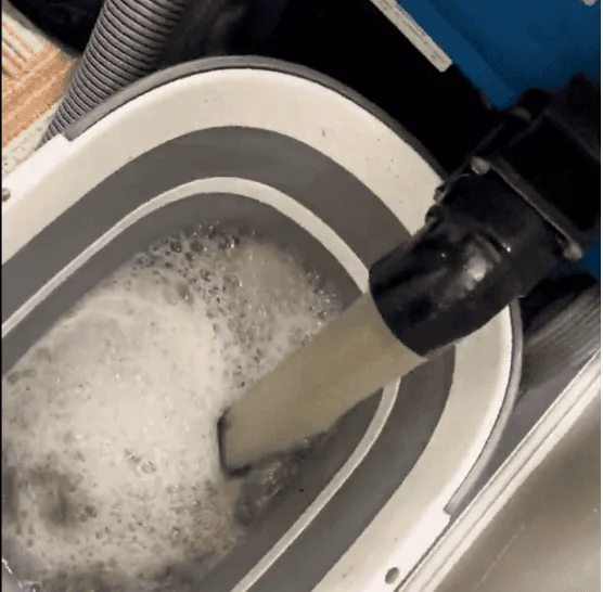 Bucket of visibly dark dirty water extracted from a carpet during a professional Cleaning Chief NYC deep carpet cleaning — proof of thorough extraction