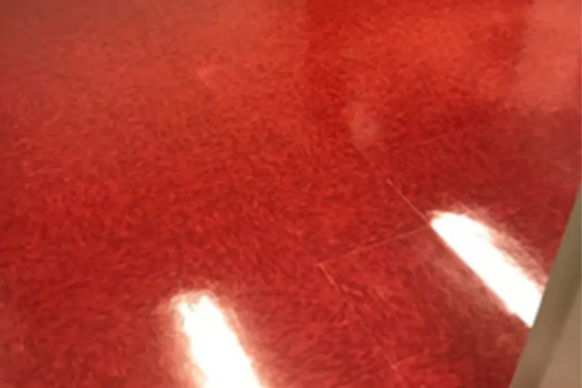 Same red stone surface now highly polished to a glass-like reflective finish with bright light spots after floor care