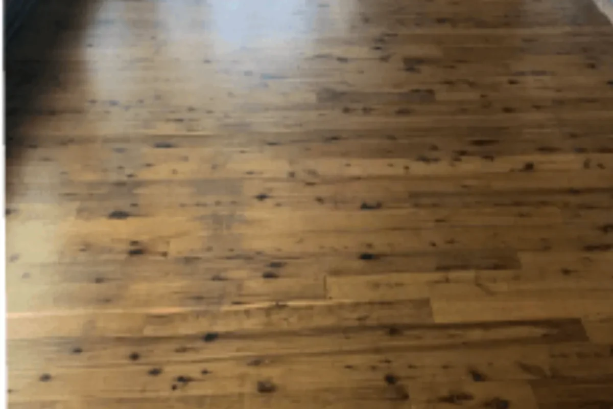 Same hardwood floor restored to natural warm honey-brown tone with stains removed after commercial floor care