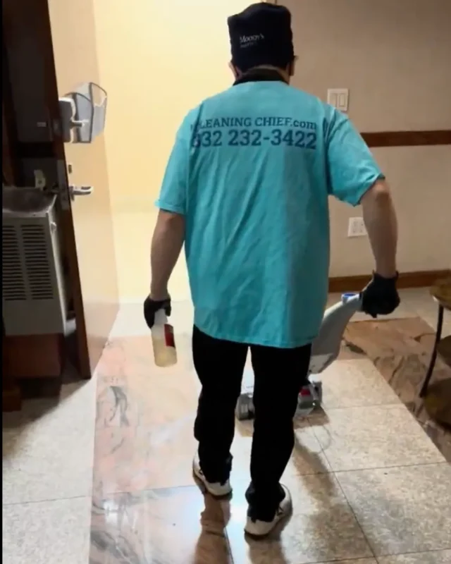 Cleaning Chief cleaner in teal shirt holding spray bottle on freshly polished marble floor in NYC commercial restroom