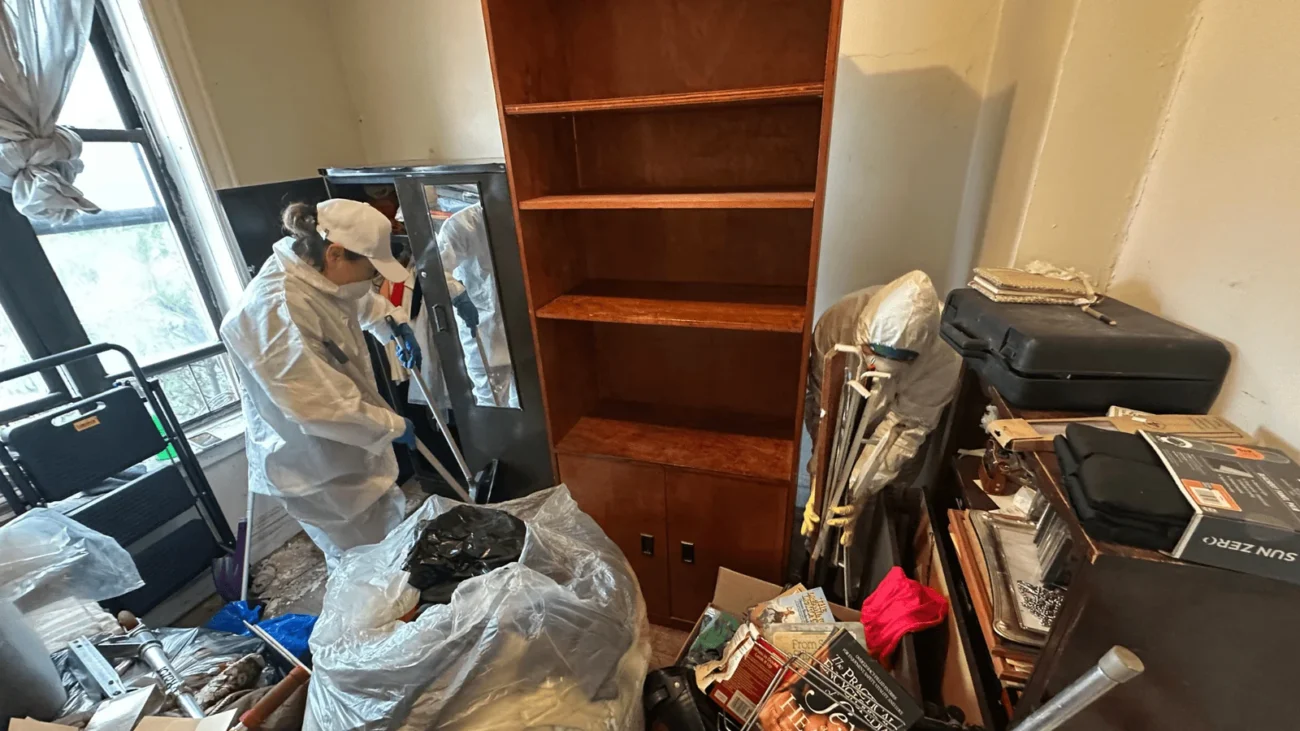 Two Cleaning Chief NYC technicians sorting and removing clutter from a heavily hoarded room in New York City