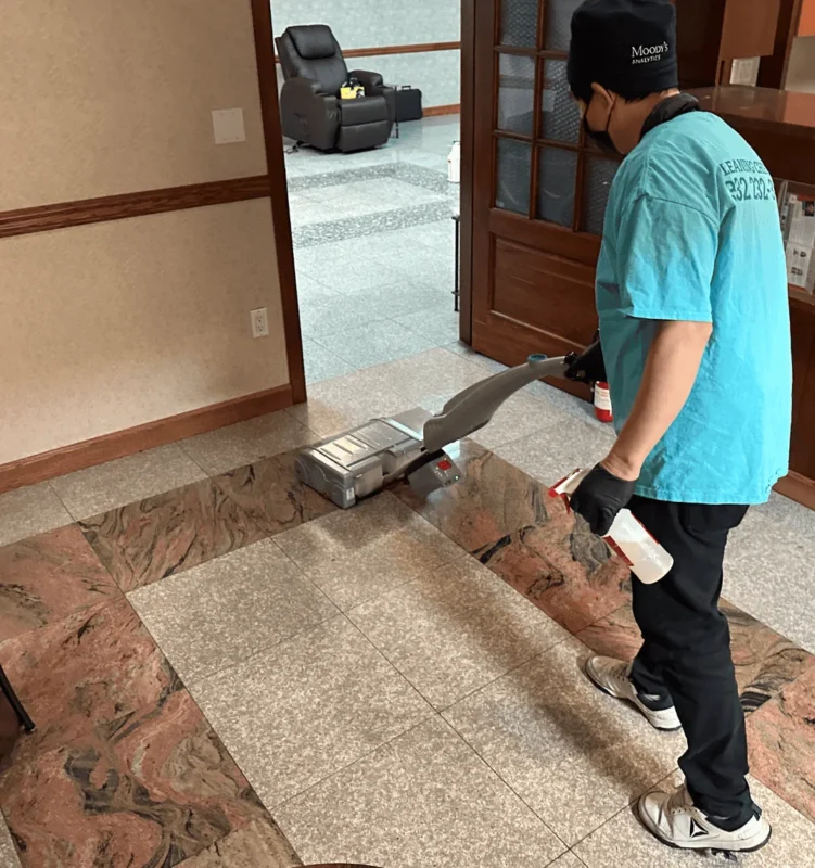 Cleaning Chief NYC technician operating a commercial autoscrubber machine on stone tile floors in a medical office