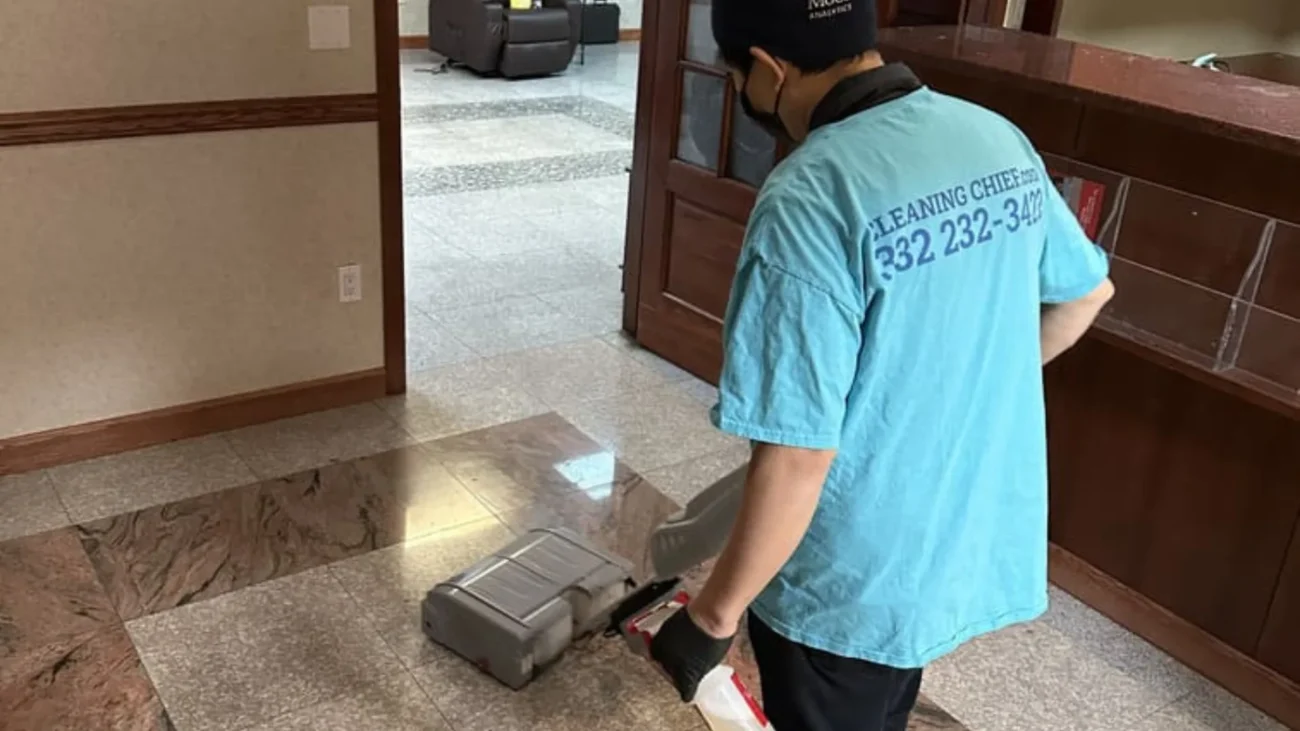 Cleaning Chief cleaner in teal shirt using compact floor scrubber on polished marble lobby floor in NYC commercial space