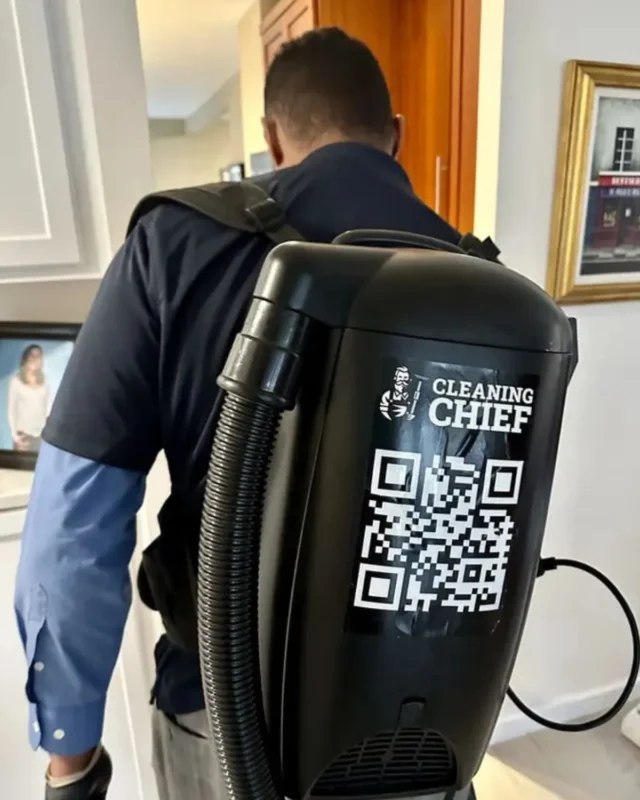 Cleaning Chief cleaner with branded backpack vacuum clearing construction dust in NYC apartment