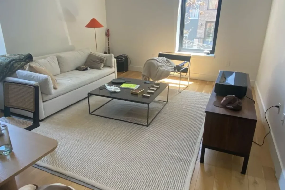 Unmade bed with rumpled sheets and cluttered bedroom before standard cleaning in NYC