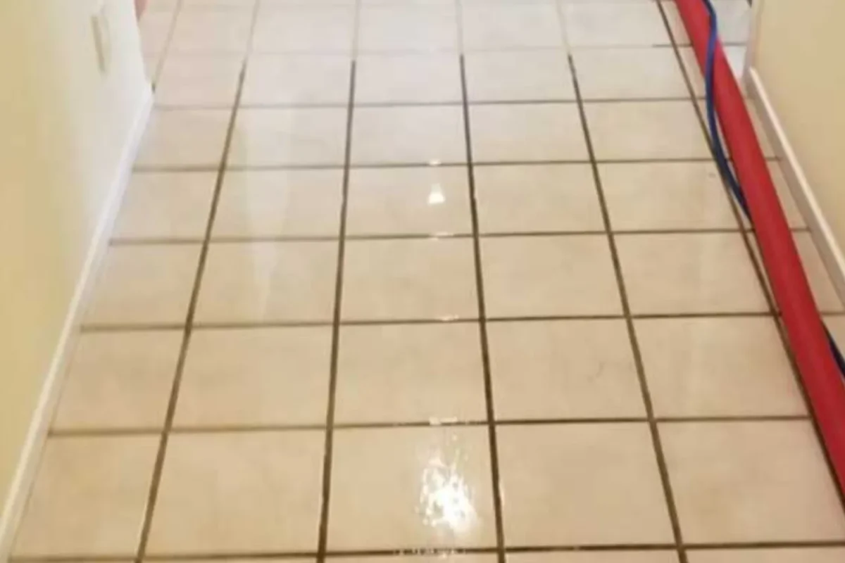 Commercial tile floor with heavily blackened grout lines and dirty standing water before power washing in NYC