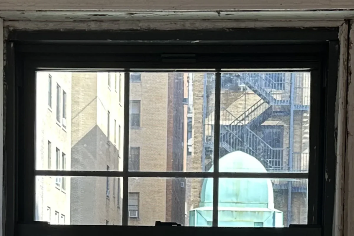 Same multi-pane NYC apartment window fully clean with clear view of buildings after professional cleaning